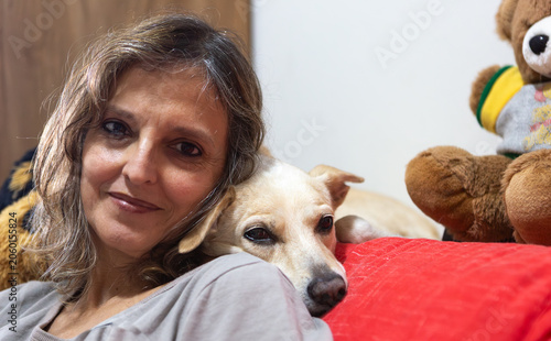 Portrait of a woman relaxing on a sofa with her dog, creating a cozy and intimate home lifestyle scene
