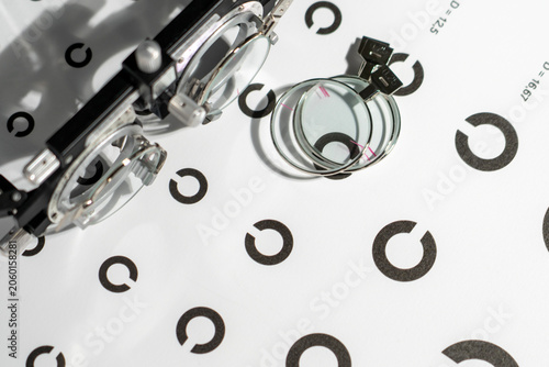 Tableau sur toile Silver eyeglass frame sits near stacked lenses