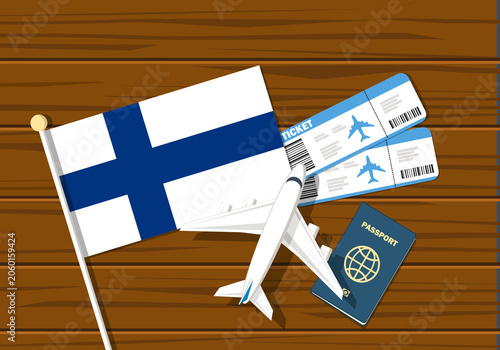 Flag off Finland with passport and toy airplane on wooden background. Flight travel concept

