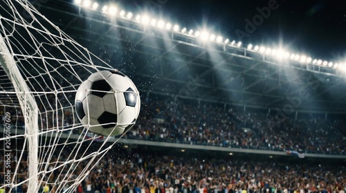 Soccer ball hitting the back of the net for a goal and blurred arena crowd