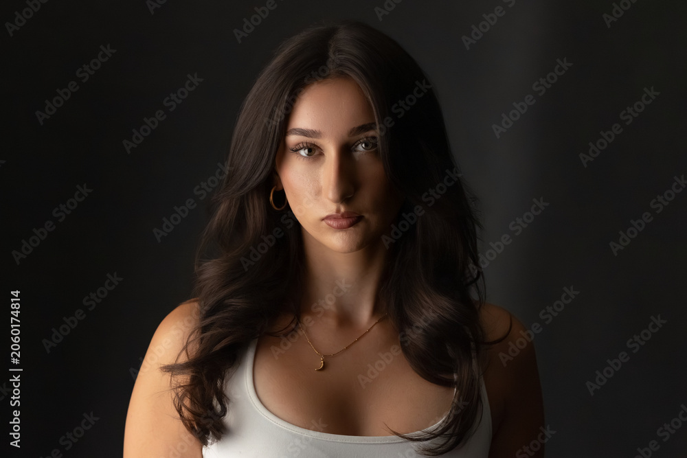 Fototapeta premium Woman looking at camera in a studio setting with a dark backdrop