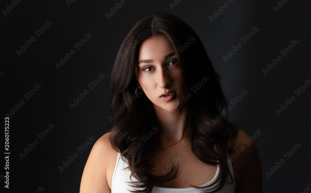 Fototapeta premium Portrait of a young brunette woman modeling with serious expression in a studio environment