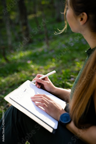 Photography Young woman recording thoughts and ideas in a notebook surrounded by nature