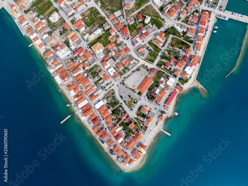 Canvas Print Aerial view of Mytikas, a tranquil Greek village on a peninsula in the Ionian Sea, with red-roofed houses, a harbor, and surrounding mountains and turquoise water