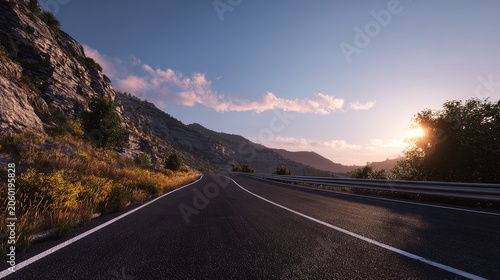 A winding asphalt road snakes through a mountainous landscape at sunrise. Sunlight reflects off the road's surface. Trees and hills surround it