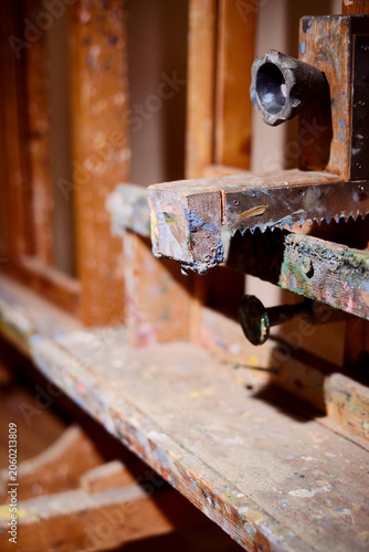 Close up of artist's easel covered in colorful paint splatters. Fragment An old artist's easel covered in paint. Shallow depth of field