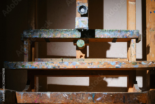 Old artist's easel covered in paint. Shallow depth of field