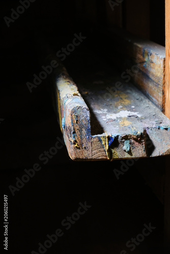 Close up of  fragment an old artist's easel covered in paint. Shallow depth of field