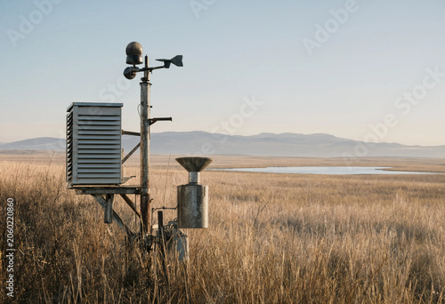 Fotografie Weather monitoring station with sensors and rain gauge standing in a dry grassy