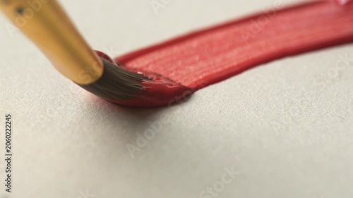 Close-up of brush bristles on paper drawing a red line with paint, oil or gouache, concept of leisure and hobby