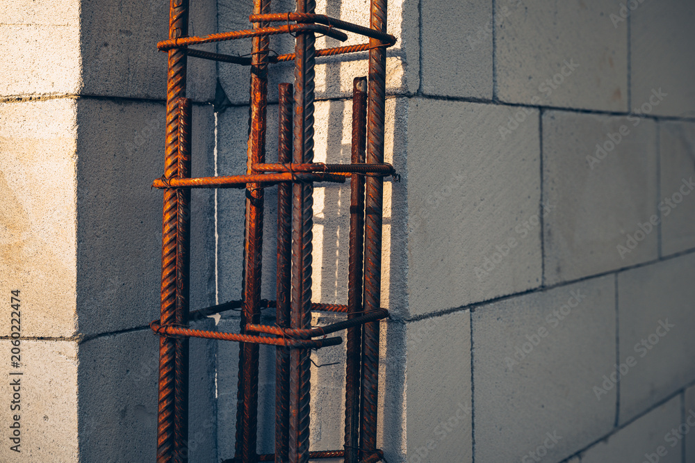 Naklejka premium Construction detail showing steel rebar reinforcement beside lightweight concrete blocks. Architecture, engineering, durability and building industry concept.