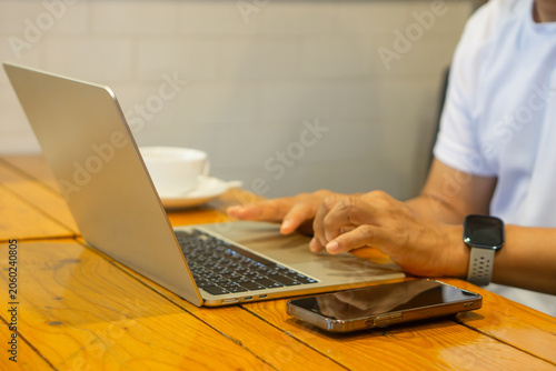 Businessman at workspace with laptop and smartphone on wooden table.