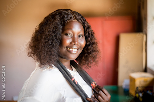 Portrait of smiling young african business woman sitting at desk in office writing and working in team on laptop,corporate jobs and economy in africa