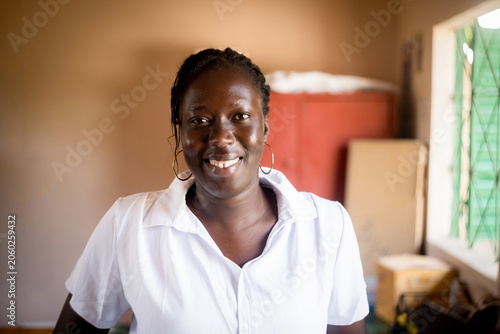 Portrait of smiling young african business woman sitting at desk in office writing and working in team on laptop,corporate jobs and economy in africa