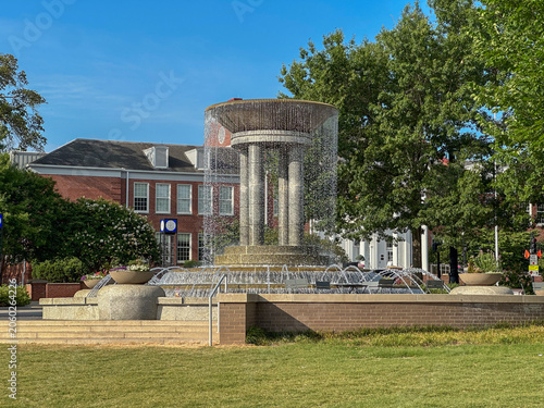 A modern cascading fountain serves as a focal point at Downtown Cary Park, surrounded by landscaped gardens and civic architecture in Cary, North Carolina.
