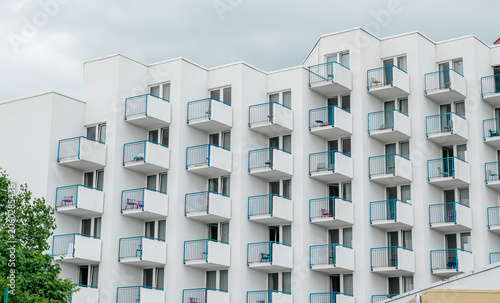Canvas Print Modern apartment building or hotel facade featuring a repeating pattern of white balconies with blue metal railings