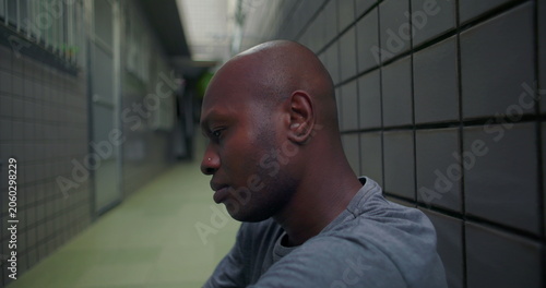 Foto African American man seated on corridor floor with pensive expression processing