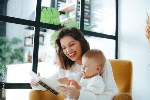 Mother and baby engaging with book in bright living room