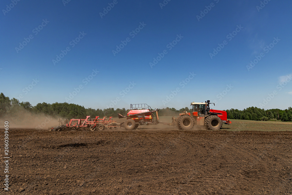 Fototapeta premium Modern tractor with seeding machine working on agricultural field