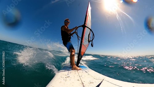 Active man windsurfing on a sun-drenched ocean, catching a wave with exhilarating speed and freedom