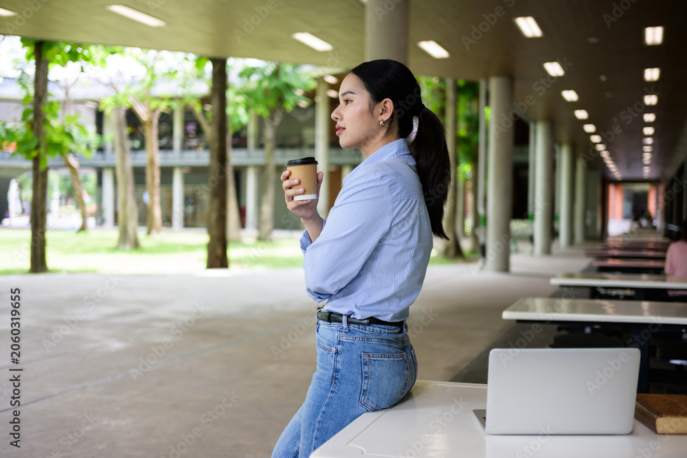 Fototapeta premium Young woman drinking coffee resting on campus