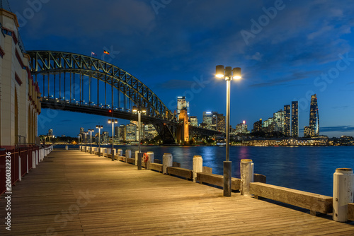 Sydney skyline and Harbour Bridge as seen from a deserted wooden boardwalk at twiligh in autumn. NSW, Australia.