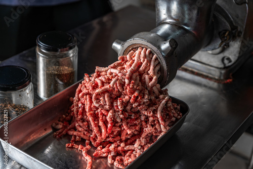 Close up video of fresh ground beef being processed through a commercial meat grinder in a professional kitchen