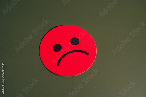 Red sad face emoji on green background, symbolizing unhappiness and negative emotion, isolated with simple design and clear expression of sadness and disappointment