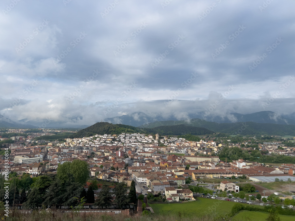 Fototapeta premium Olot city panorama with clouds covering mountains