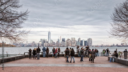 Tourists and visitors enjoying urban exploration and sightseeing at the waterfront with scenic views of the skyline, travel and tourism lifestyle, Liberty Island, New York City, USA.