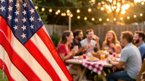 crisp american flag foreground framing a joyful golden hour fourth of july backyard cookout with friends laughing under string lights