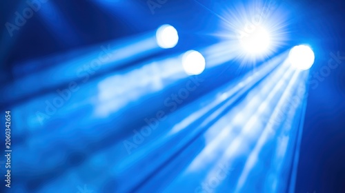 Vibrant blue stage lighting with bright spotlights creating dynamic beams and ethereal bokeh effects for performances