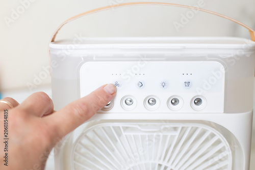 Finger pressing button on portable misting fan control panel