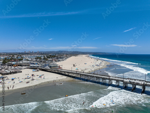 The Newport Beach Pier Area in California from a UAV Drone looking at waves near the shore and the way they break on the beach with the pier on right