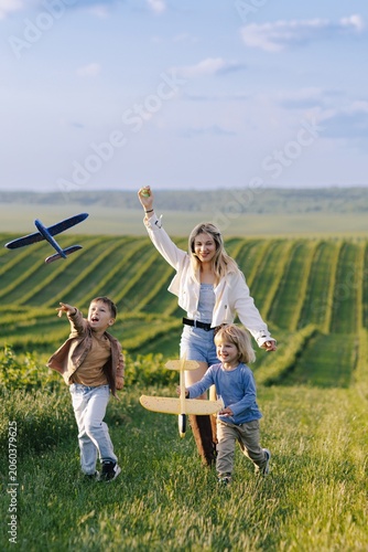 Family playing with toy planes in summer field