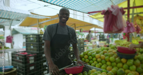 Canvas Print African American street vendor leaning on produce stall smiling at camera reflec