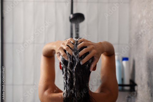 Принти на полотні Back view of lady applying shampoo and washing hair under shower, doing haircare