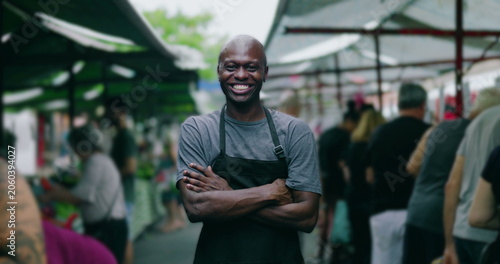 Photos African American street vendor with arms crossed smiling at outdoor market conve