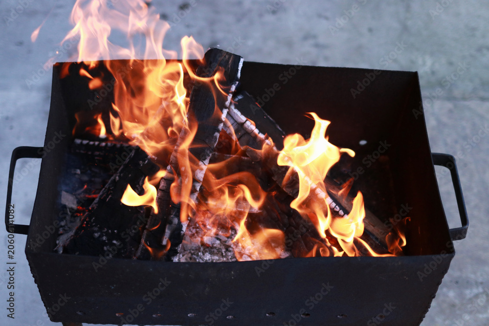 Fototapeta premium Outdoor brazier with burning wood and bright orange flames