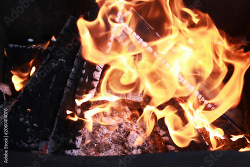 Charred wood burning with bright flames in outdoor grill