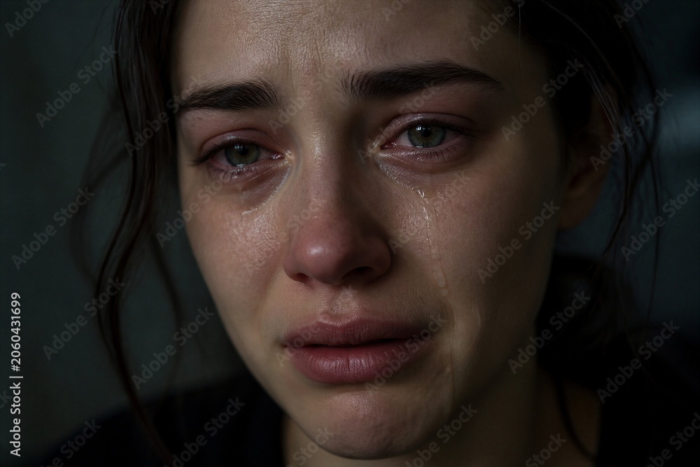 Fototapeta premium Young woman tearful with wet cheeks close up portrait indoors