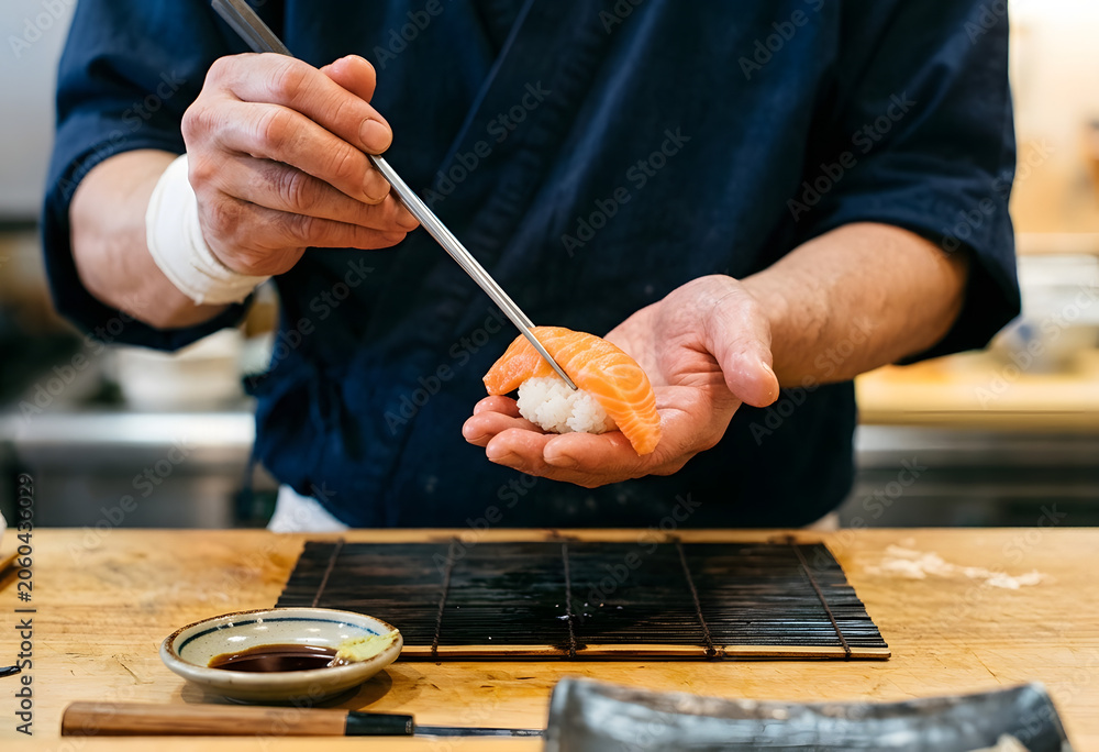 Obraz premium Professional chef preparing salmon nigiri sushi in traditional restaurant