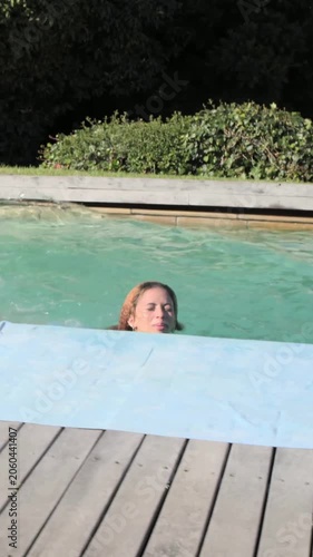 Vertical video: Running jumper jumping into home pool to join friends in swimwear by towel phone