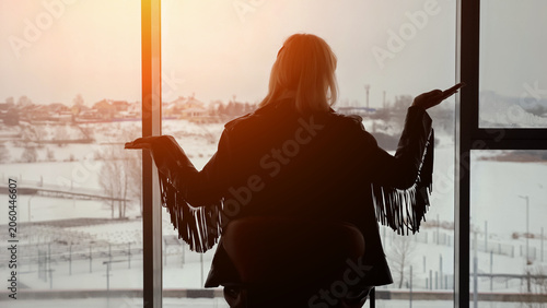 Konstfotografi Woman silhouette looking out of a large window with open arms, observing the ser