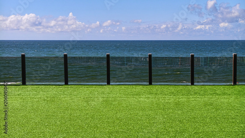 Modern terrace with green lawn overlooking the blue sea