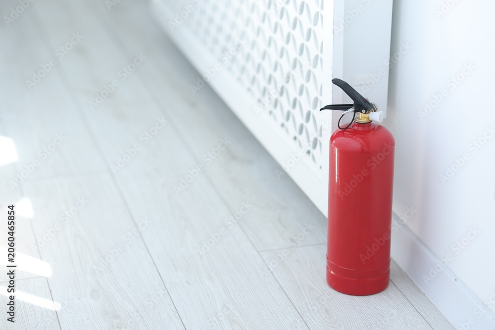Obraz premium One red fire extinguisher on floor indoors, space for text