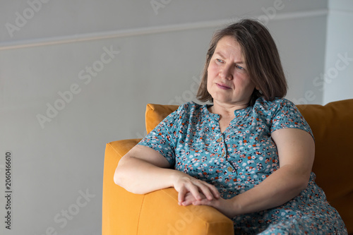 Thoughtful Lady Relaxing With Contemplative Mood. Serene Woman Leaning On Sofa Exhibiting Introspective Demeanor. Quiet Female Immersed In Thought While Leaning Against Sofa With Peaceful Expression