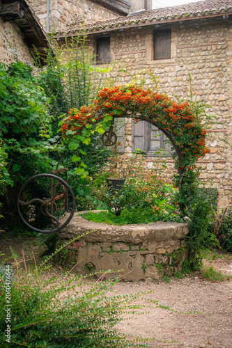 Foto Puits ancien avec arche fleurie dans cour de village médiéval