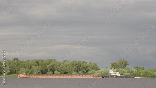 A tugboat is pushing a long barge down the wide river