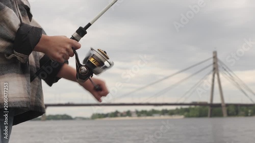 A little boy is fishing on a big river using a spinning rod